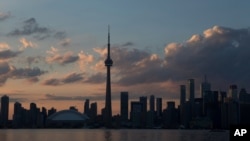 FILE - The sun sets on the Toronto skyline, July 10, 2015. 