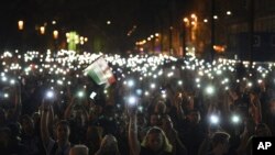Para pengunjuk rasa mengangkat telepon selular dengan layar menyala selama rapat akbar yang diselenggarakan oleh gerakan yang disebut Freedom for Education, dengan tema CEU Now, Who’s Next-Protest for the Free Education, di depan gedung Parlemen di Budapest, Hungaria hari Minggu, 2 April 2017 (foto: Zoltan Balogh/MTI via AP)