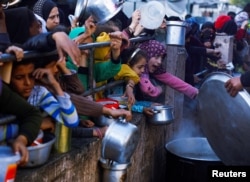 Palestinska deca čekaju da dobiju hranu tokom svetog muslimanskog meseca Ramazana, dok se nastavlja sukob Izraela i Hamasa, u Rafi, na jugu Pojasa Gaze, 13. marta 2024.