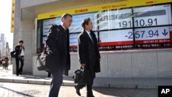 人们从日本东京一证交所外的电子股指显示器旁走过。（资料图）