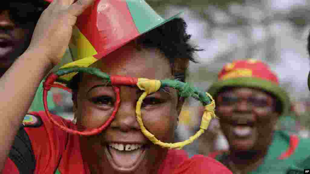 Les amateurs du football camerounais sourient à un photographe à l'aéroport international de Malabo à Malabo, Guinée équatoriale samedi 17 janvier 2015.