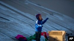 Un niño migrante llora para tratar de llamar la atención de su padre mientras su familia aguarda en la orilla sur de Río Grande para cruzar a El Paso, Texas, desde Ciudad Juárez, México, el miércoles 21 de diciembre de 2022 (Foto AP/Andres Leighton)