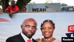 Un partisan de l'ancien footballeur et candidat à la présidence du Congrès pour le changement démocratique (CDC) George Weah se tient derrière une bannière de la campagne présidentielle à Monrovia, Libéria, le 6 octobre 2017.