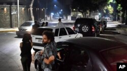 People stand close to their vehicles as they wait in line to fill up their vehicles with gasoline in Caracas, Venezuela, April 11, 2020.