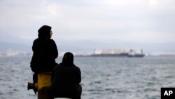 Deux femmes sont assises sur un quai d'un camp de réfugiés qui abrite environ 3.200 réfugiés et migrants, dans la banlieue ouest de Skaramagas, à Athènes, le 25 août 2016.