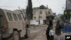 Una mujer palestina hace una señal de V hacia las tropas israelíes durante una redada del ejército en el campo de refugiados de Tulkarem, Cisjordania, el miércoles 17 de enero de 2024.