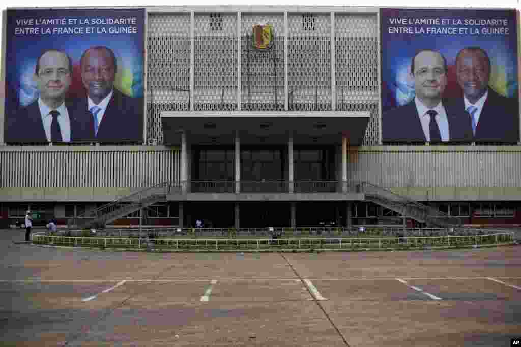 Des affiches géantes mettant en vedette le président français François Hollande et son homologue guinéen Alpha Condé sur la façade du Palais du Peuple à Conakry, en Guinée, mercredi 26 novembre 2014.