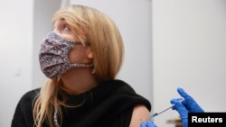 Una mujer mira hacia otro lado mientras recibe una dosis de la vacuna COVID-19 en un centro de vacunación en Londres, Gran Bretaña, el 15 de diciembre de 2021.