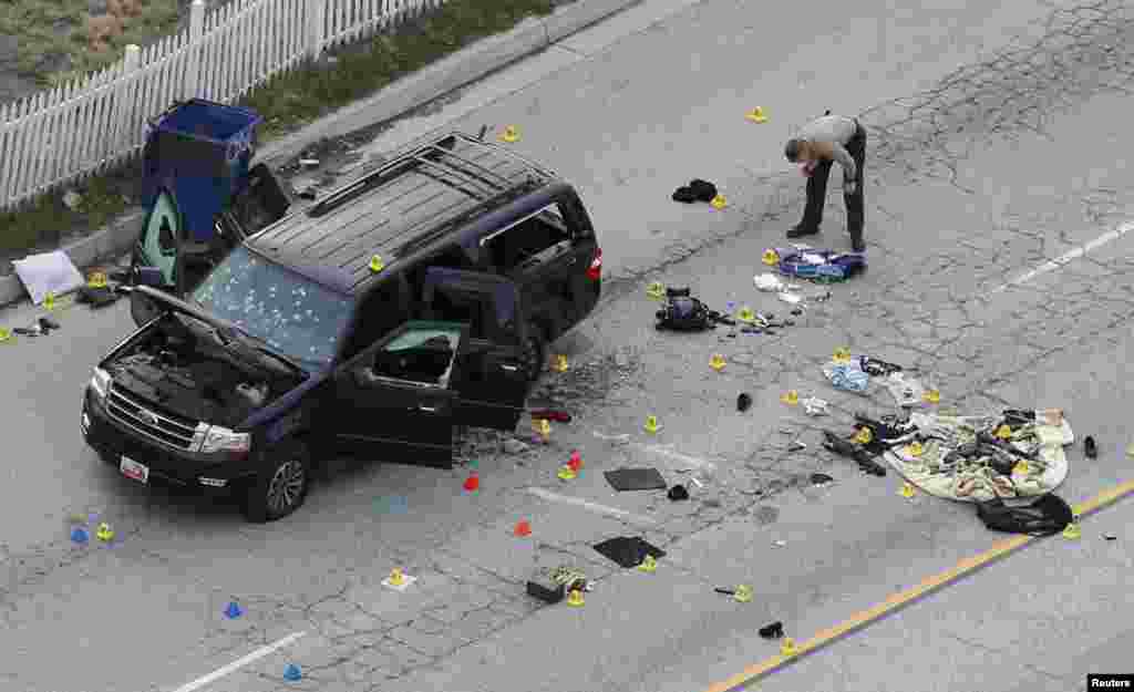 A law enforcement officer looks over the evidence near the remains of a SUV involved in the Wednesday's attack in San Bernardino, California, Dec. 3, 2015. Authorities were working to determine why a man and a woman opened fire at a holiday party of his co-workers in Southern California, killing 14 people and wounding 17 in an attack that appeared to have been planned.