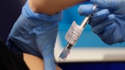 A volunteer is injected with a vaccine as part of an Imperial College vaccine trial, at a clinic in London, Aug. 5, 2020.