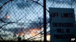 FILE - Concertina wire is overgrown with foliage at the now closed Camp X-Ray, which was used as the first detention facility for al-Qaida and Taliban militants who were captured after the Sept. 11 attacks at Guantanamo Bay Naval Base, Cuba.