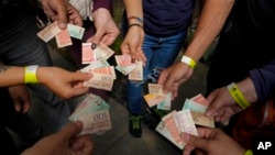Turistas muestran los billetes viejos de bolívares para usarlos como tiques para intercambiarlos por comida en un tour realizado en Caracas, Venezuela, el 21 de agosto de 2021. La inflación entre enero y junio fue de 100 puntos, según una organización no gubernamental.