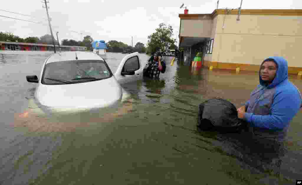 Conception Casa, center, and his friend Jose Martinez, right, check on Rhonda Worthington after her car become stuck in rising floodwaters from Tropical Storm Harvey in Houston, Texas, Monday, Aug. 28, 2017. The two men were evacuating their home that had become flooded when they encountered Worthington's car floating off the road. (AP Photo/LM Otero)