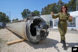 Wakil kepala departemen pers Internasional IDF militer Israel, letnan satu Masha Michelson, menunjukkan kepada media salah satu rudal balistik Iran yang dicegat Israel selama akhir pekan, di pangkalan militer Julis, Israel selatan, Selasa, 16 April 2024. (Foto: AP)