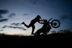El motociclista Pedro Aldana realiza un caballito en su motocicleta durante una exhibición en el barrio Ojo de Agua de Caracas, el 10 de enero de 2021. [Foto: AP].