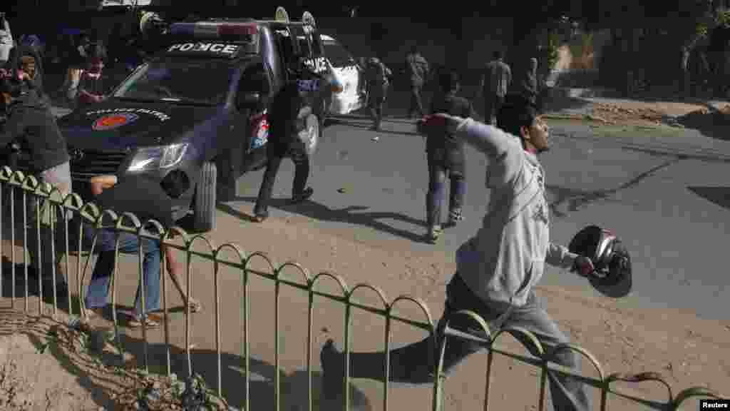 Les partisans du Jamiat Talaba l'Islam (ITC), l'aile étudiante du Jamaat Islami (JI), jettent des pierres sur des policiers lors d'une manifestation contre l'hebdomadaire satirique français Charlie Hebdo, Karachi, au Pakistan, le 16 janvier 2015.