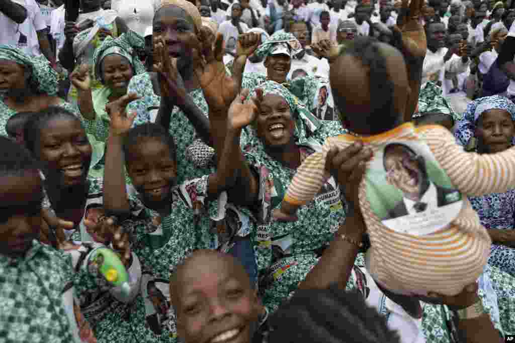 Women and girls wearing outfits made of wax cloth depicting presidential candidate Soumaila Cisse dance and hold up a baby, also decorated with a campaign sticker, during a campaign rally in Bamako, Mali, July 20, 2013.