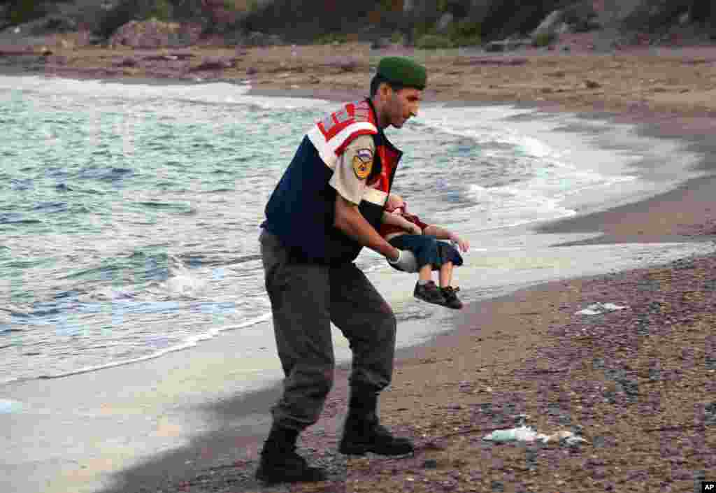 A paramilitary police officer carries the lifeless body of a migrant child, lifting it from the seashore near the Turkish resort of Bodrum, Sept. 2, 2015.