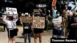 People hold placards as they gather for a protest outside the Kenosha County Courthouse, August 24, 2020, after a Black man, identified as Jacob Blake, was shot several times by police Sunday night in Kenosha, Wisconsin. 