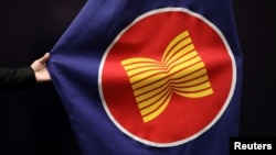 រូបឯកសារ៖ បុគ្គលិក​ម្នាក់ កាន់​ទង់​អាស៊ាន ដែល​ត្រូវ​បាន​គេ​ដោត​តាំង​នៅ​សាល​ប្រជុំ​ក្នុង​ទីក្រុង​គូឡាឡាំពួ ប្រទេស​ម៉ាឡេស៊ី កាលពី​ថ្ងៃ​ទី​២៨ ខែ​តុលា ឆ្នាំ​២០២១។