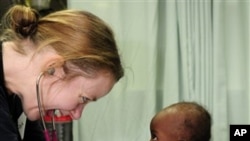 In this 21 Jan 2010 photo, Lt. Jerri Gram, from Huntsville, Ala., a doctor aboard the Military Sealift Command hospital ship USNS Comfort, shares a smile with a female infant during an examination off the coast of Port-au-Prince, Haiti.