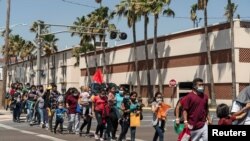 Familias de inmigrantes marchan hacia un albergue temporal en McAllen, Texas, EE. UU., el 8 de abril de 2021.