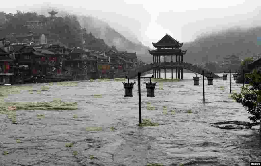 Street lamps are seen among floodwaters next to partially submerged buildings by an overflowing river at an ancient town as heavy rainfall hits Fenghuang county, Hunan province, China.