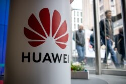 A pedestrian walks past a Huawei product stand at an EE telecommunications shop in London, April 29, 2019