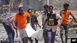 Sejumlah warga dan petugas penyelamat mengevakuasi jenazah seorang warga sipil yang tewas akibat sebuah ledakan di Mogadishu, Somalia, pada 12 Januari 2022. (Foto: AP/Farah Abdi Warsameh)