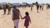 ARCHIVO - Un hombre camina con un niño por la aldea Doña Ana de Fort Bliss, donde se alojaban refugiados afganos, en Nuevo México, el 10 de septiembre de 2021.