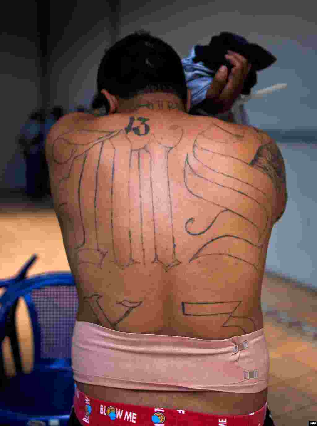 Un supposé membre du gang MS-13 couvre son visage lors d'une arrestation à San Salvador, le 31 janvier 2014.