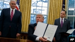 President Donald Trump shows an executive order to withdraw the U.S. from the 12-nation Trans-Pacific Partnership trade pact Jan. 23, 2017. With him are Vice President Pence (L) and Chief of Staff Reince Priebus. (AP Photo/Evan Vucci)