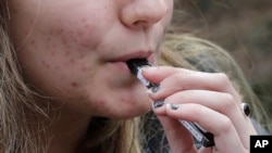 Seorang siswi SMA mengisap vape dengan alat merokok buatan "Juul Labs" di Cambridge, Massachusetts, AS (foto: ilustrasi). 