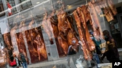 Kaca jendela sebuah restoran yang menjual bebek panggang di Lima, Peru, memantulkan bayangan para pejalan kaki yang melewati jalanan di depannya, di tengah pandemi Covid-19, 11 Juli 2020. (AP Photo/Rodrigo Abd)