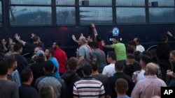 Protesters rock a riot police bus in the town of Mytilene on the northeastern Aegean island of Lesbos, May 3, 2018. 