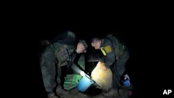 ARCHIVO - La policía antinarcóticos inspecciona el uso de químicos en la producción de base de coca antes de quemar un laboratorio en una zona rural de Orito, estado de Putumayo, Colombia, en abril de 2022.