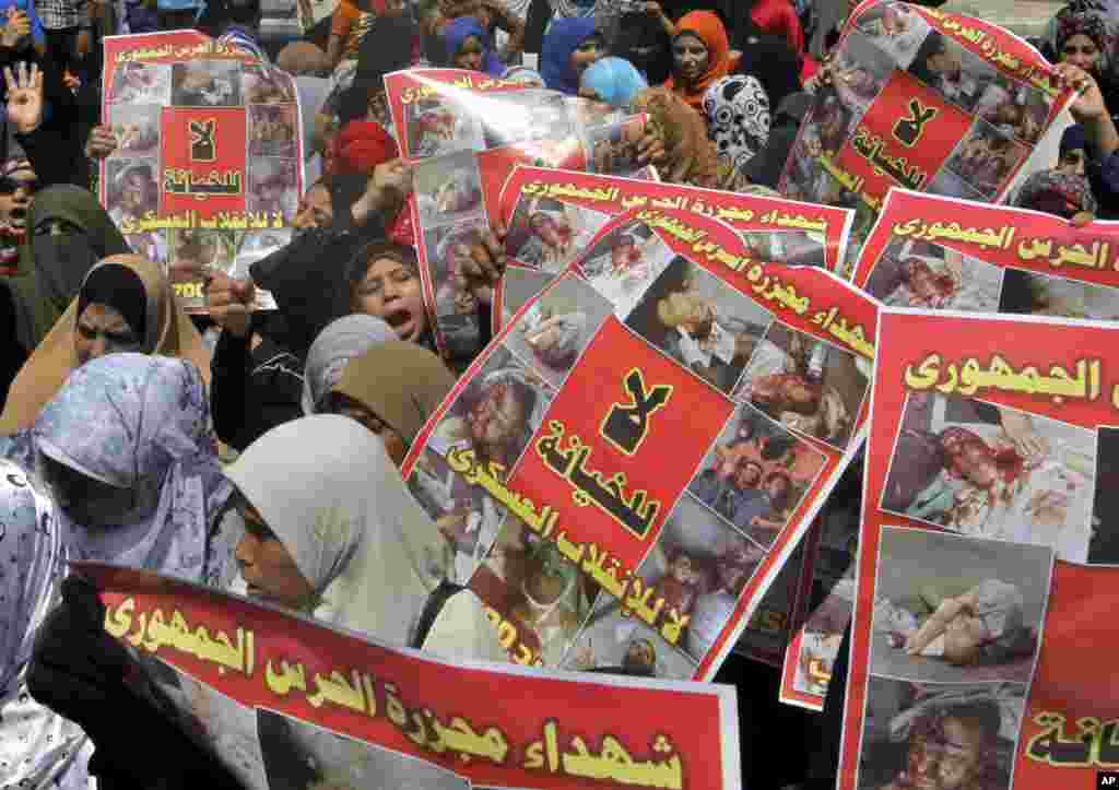 Para pendukung presiden terguling Mesir Mohamed Morsi memegang poster bergambar para korban kekerasan militer di kamp protes mereka dalam aksi protes di Kairo, 23 Agustus 2013.