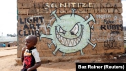 A boy stands in front of a graffiti promoting the fight against the coronavirus disease (COVID-19) in the Mathare slums of Nairobi, Kenya, May 22, 2020. (REUTERS/Baz Ratner)