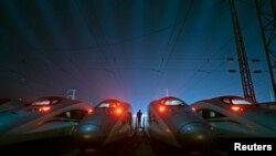 FILE - A worker stands among CRH (China Railway High-speed) Harmony bullet trains at a high-speed train maintenance base in Wuhan, Hubei province, March 9, 2015. 