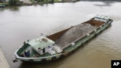 FILE - A Vietnamese vessel hauling sand plies the Tatai River in southwestern Cambodia, Aug. 2, 2011. Cambodia once exported vast amounts of sand for land reclamation and construction projects in Singapore. The government has since banned exports of most types of sand, but exempted silica sand from the ban.