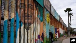 A man looks through the first wall at Friendship Park, near where the border separating Tijuana, Mexico, and San Diego meets the Pacific Ocean Tuesday, Jan. 19, 2021, in Tijuana, Mexico. In the days before Joe Biden became president, construction…