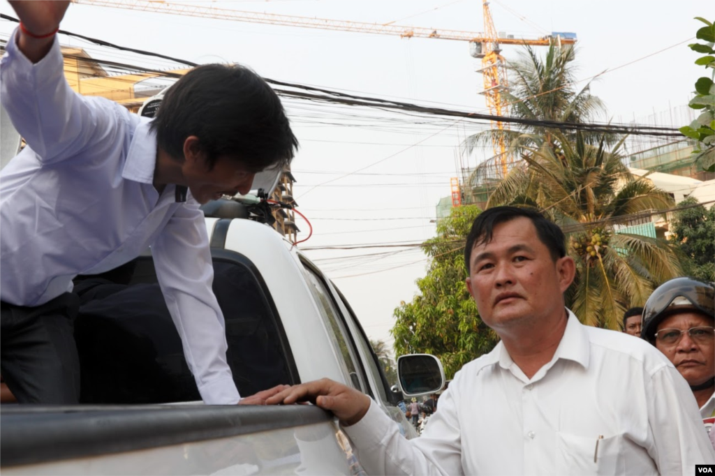 Srey Chamroeun, who led some 70 of the self-claim university students, talks a representative of Toul Kork district during a Tuesday protest in front of Kem Sokha's house. The group, which called by public as a VIP protester group, was safeguarded by local authorities for the parade in Phnom Penh on March 29, 2016. (Leng Len/VOA Khmer)
