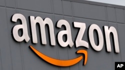 A sign is lit on the facade of an Amazon fulfillment center, Thursday, March 19, 2020, on Staten Island in New York. The company plans to hire another 100,000 new workers in their fulfillment centers to fill increased customer demand during the…