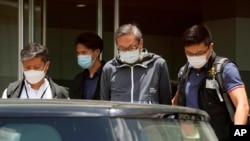 Police officers escort Cheung Kim-hung, right, CEO and executive director of Next Digital Ltd at Apple Daily headquarters in Hong Kong, June 17, 2021. 