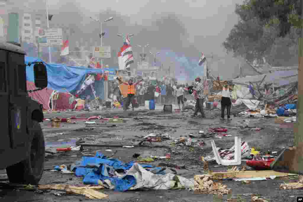 Para pendukung presiden terguling Mohamed Morsi berdiri di atas puing-puing dan di antara asap menyusul bentrokan dengan pasukan keamanan di Kairo. (AP/Imad Abdul Rahman)