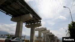 FILE - Commuters drive past a construction site by Odebrecht of the Caracas-Guatire metro rail project in Guatire, Venezuela, March 28, 2017.