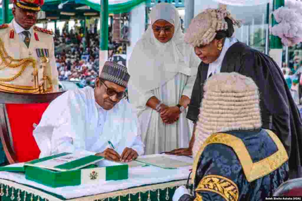 Shugaba Buhari yana rattaba hannu a gaban babban jojin Najeriya bayan da ya yi rantsuwar kama aiki a wa'adi na biyu