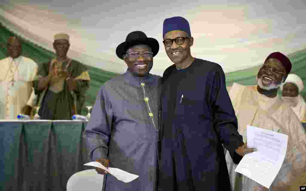 Nigeria's President Goodluck Jonathan, center-left, and opposition candidate Gen. Muhammadu Buhari, center-right, hug and shake hands after signing a renewal of their pledge to hold peaceful "free, fair, and credible" elections, at a hotel in the capital