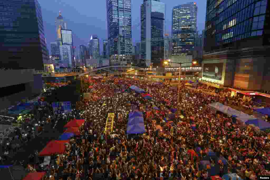 Para demonstran pro-demokrasi memegang spanduk dan menyalakan lampu dari ponsel mereka dalam peringatan satu bulan protes, di distrik keuangan Hong Kong (28/10). (Reuters/Damir Sagolj)