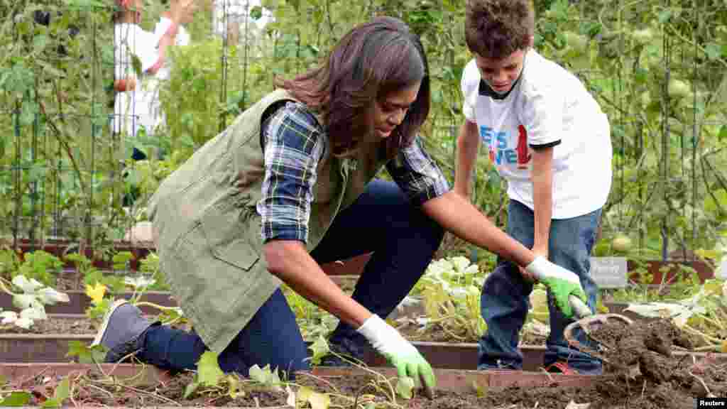 First Lady Michelle Obama helps a youngster harvest vegetables in the White House Kitchen Garden, Oct. 6, 2016.
